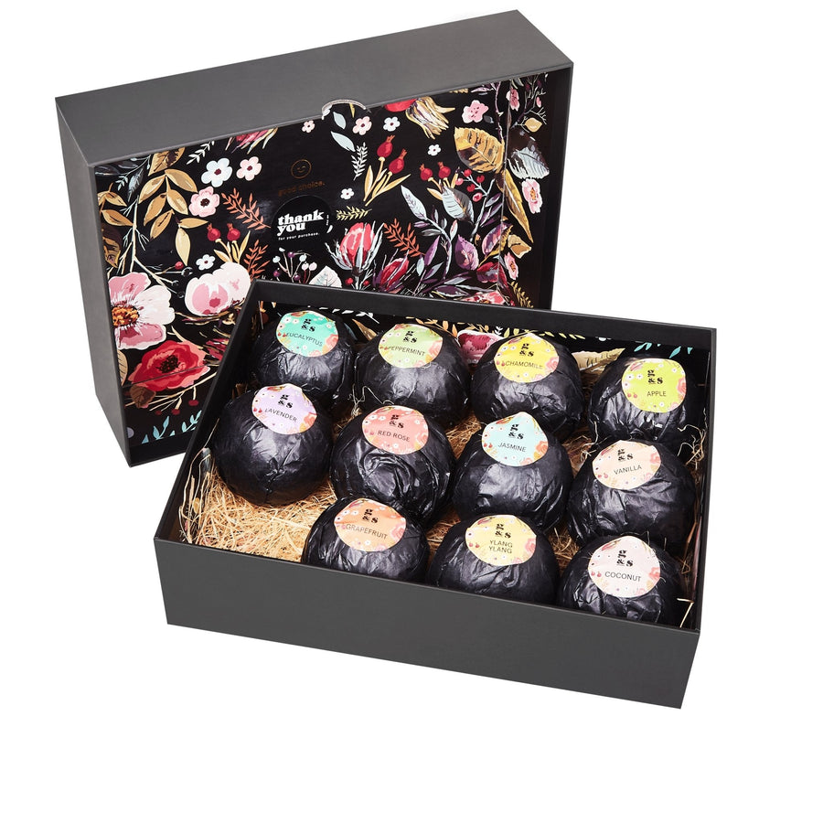 An open gift box filled with individually wrapped grace & stella bath bombs displayed on a bed of straw.
