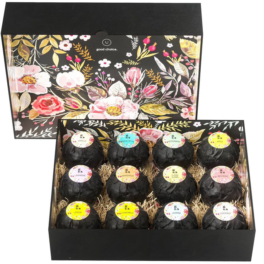 An open decorative box filled with individually wrapped grace & stella spa-quality bath bombs nestled in straw, featuring floral patterns on the interior lid.