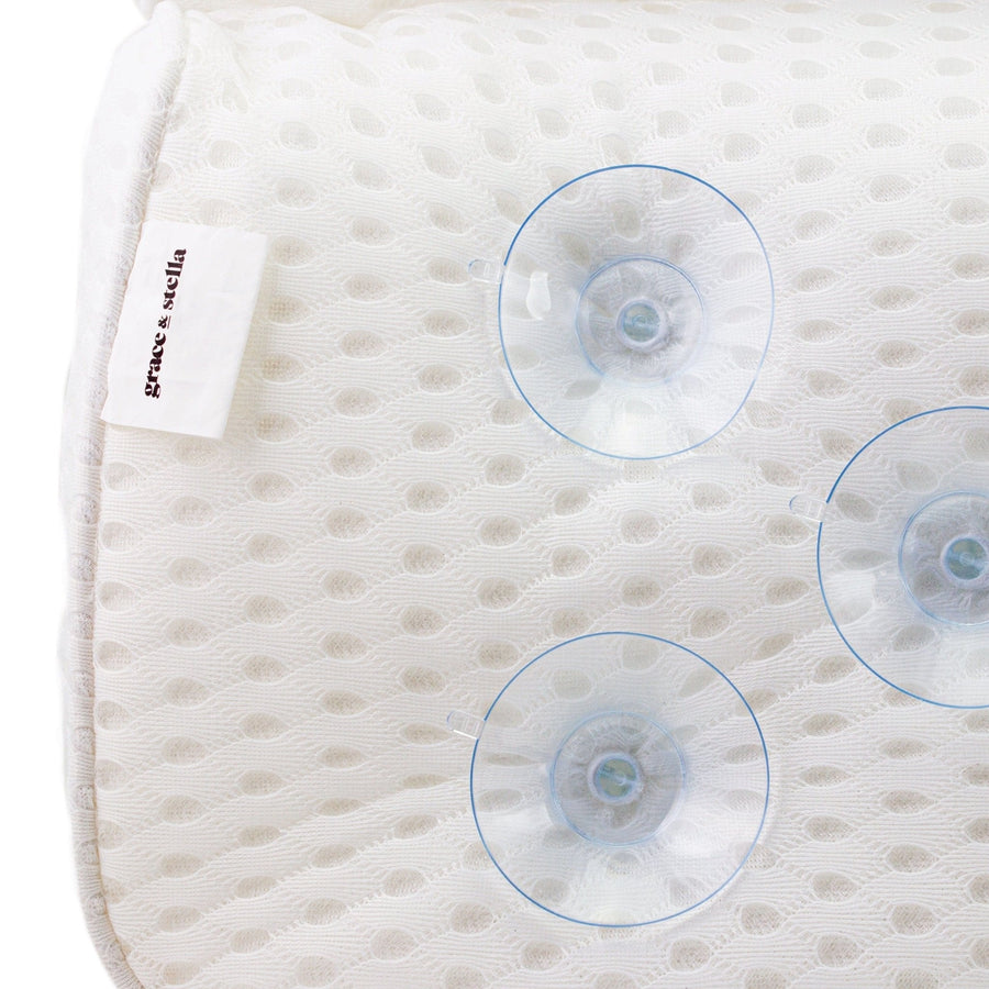A close-up of a white textured Grace & Stella bath pillow with pressure sensor indicators and a label that reads "prime labels", designed for relaxation and comfort.