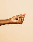 A person's hand squeezing a Grace & Stella Co. Konjac Facial Cleansing Sponge, with water droplets visible against a plain background.