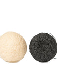 Two Grace & Stella Co. Konjac Facial Cleansing Sponges, one white and one black, isolated on a white background.