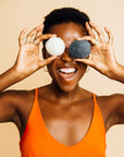 A person holding two Grace & Stella Co. Konjac Facial Cleansing Sponges over their eyes and smiling.