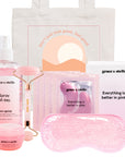 A collection of pink-themed beauty products including the Grace & Stella La Vie En Rose Set, with a fresh rose spray, a facial roller, and an eye mask, all packaged in a tote bag.