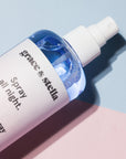 A bottle of grace & stella lavender spray on a dual-toned pink and blue background.