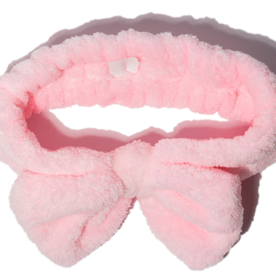 Pink fluffy bow headband and grace & stella co. silicone face mask applicator brushes on a white background.
