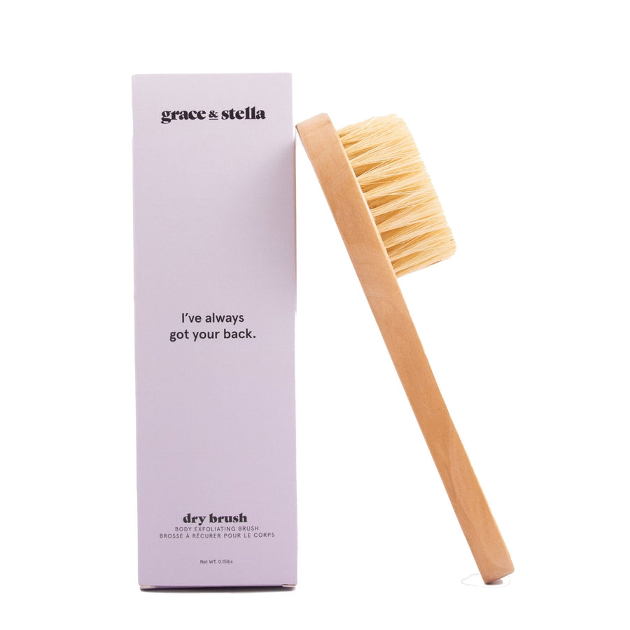 A wooden grace & stella dry brush placed next to a box for skin exfoliation.