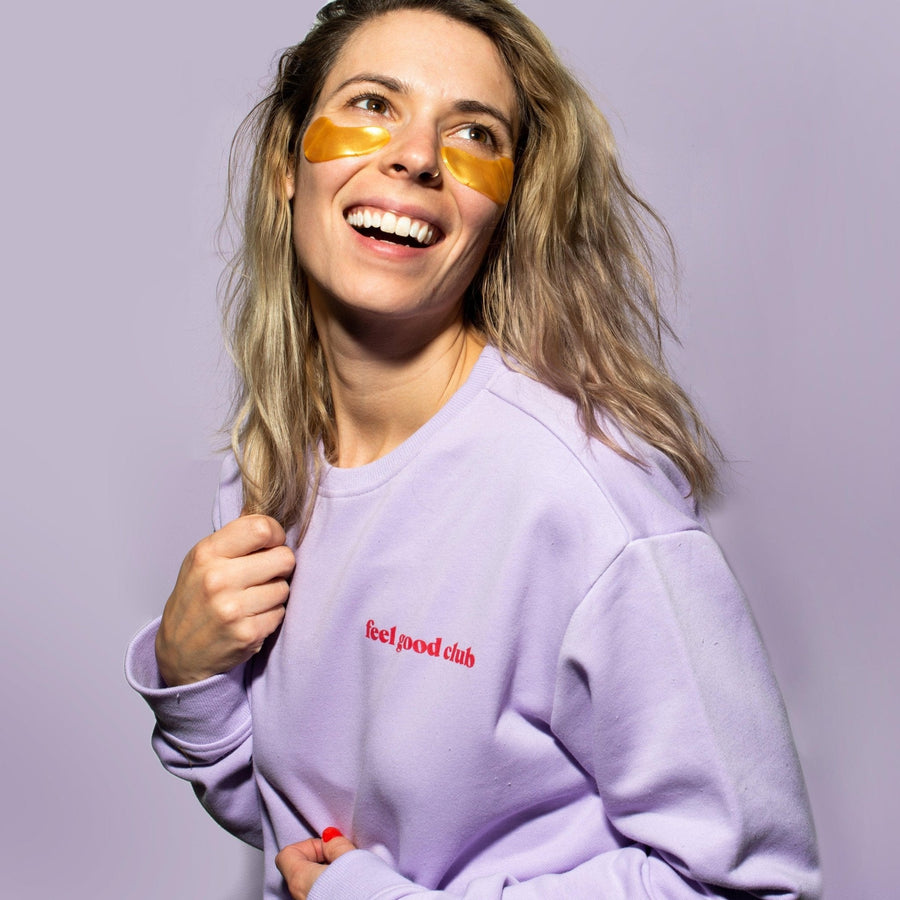 A woman in a feel-good club lilac crewneck sweater from grace & stella, feeling good with a smile on her face.