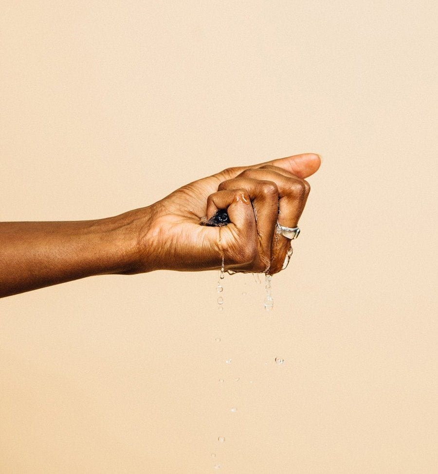 A woman's hand with a drop of water, showcasing her skin's hydration using Grace & Stella Co.'s konjac facial cleansing sponges.