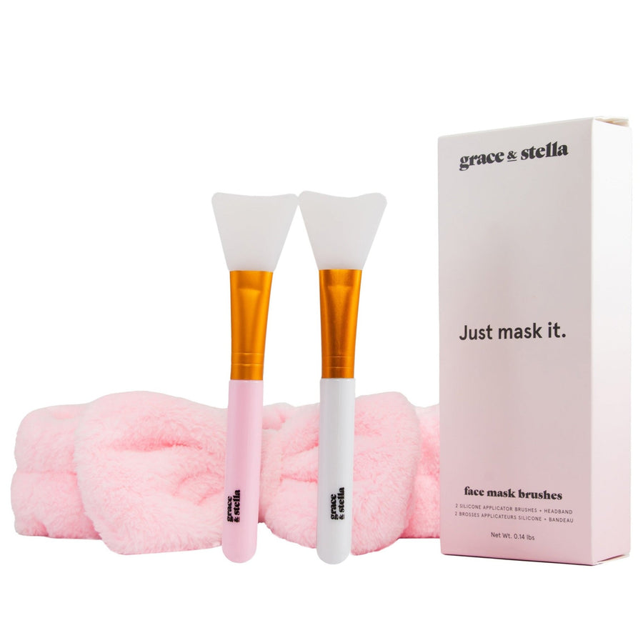 Two grace & stella co. silicone face mask brushes with pink handles alongside a matching pink headband, and a product box with the text "grace & stella - just mask it.