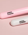 Two pink and white silicone face mask brushes and headband by grace & stella co. on a pink background.
